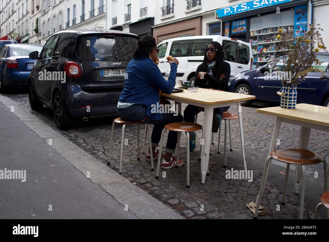 Les Parisiens bénéficient d'une terrasse de café temporaire, entre les voitures garées dans la vie après verrouillage - rue Muller, Montmartre 75018 Paris, France Banque D'Images