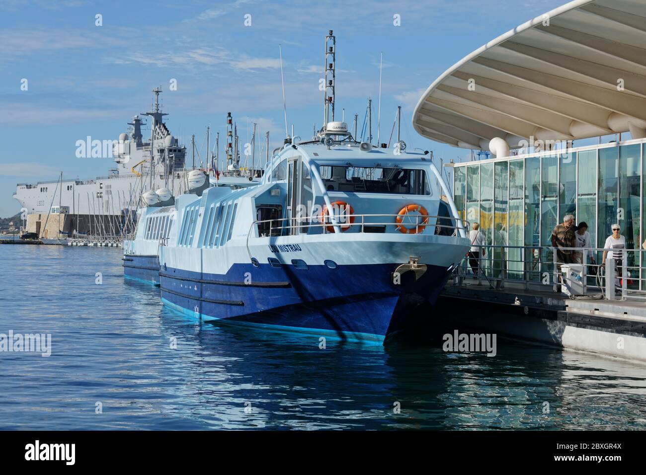 Toulon, France - 24 septembre 2019 : bateau-bus à l'embarcadère contre le navire amphibie Mistral. Les bateaux-bus de la ville de Toulon font partie du système de transports en commun Banque D'Images