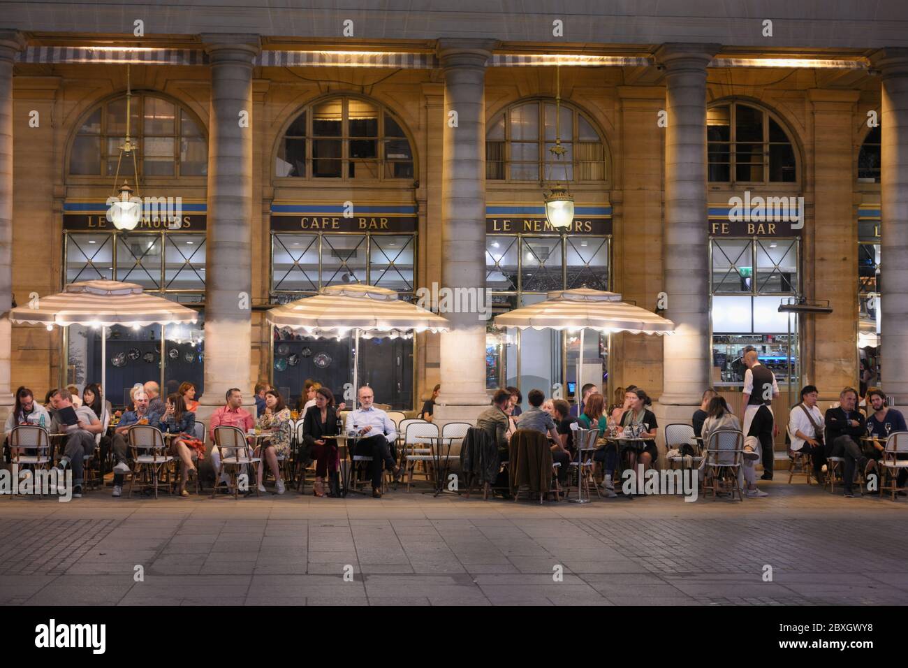Paris, France - 21 septembre 2019 : personnes se reposant sur une terrasse de rue d'un café le Nemours. Situé à côté de la Comédie française et du Palais Royal, ce café est populaire auprès des touristes et des habitants Banque D'Images