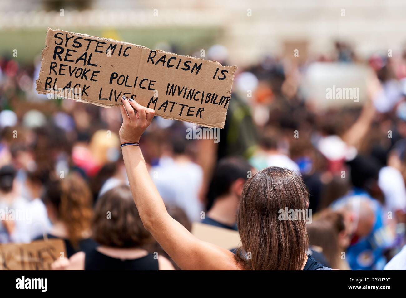 Les vies noires comptent, protestent contre le racisme pour George Floyd. Une jeune femme qui porte un signe: 'Le racisme systémique est réel. Révoquer l'invincibilité de la police » Banque D'Images