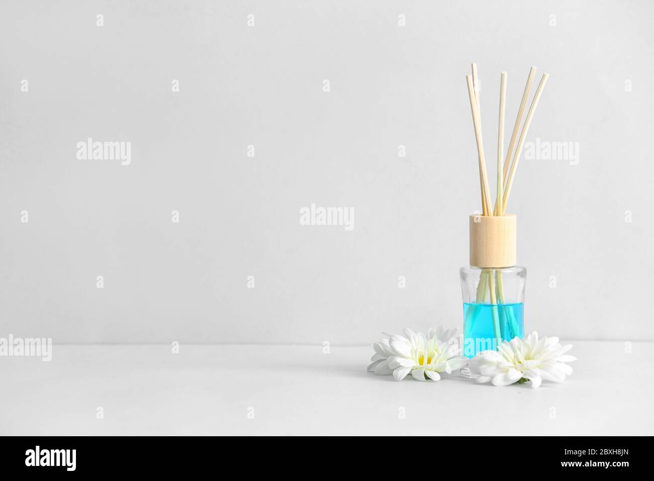 Diffuseur en roseau et fleurs sur table lumineuse Banque D'Images