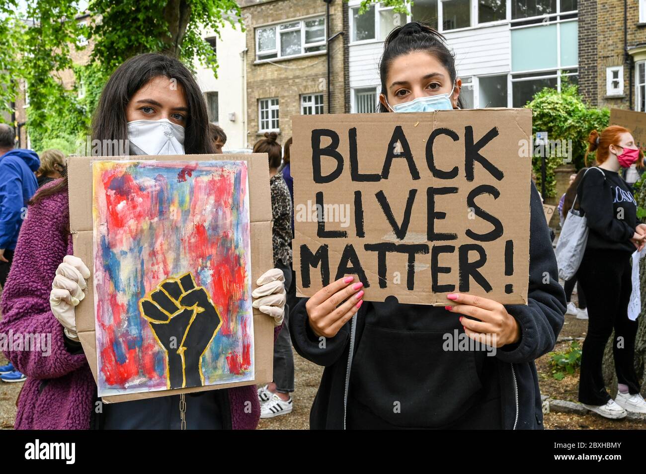 Deux jeunes femmes avec des pancartes « les vies noires comptent ! » Et une illustration d'un poing noir lors d'une manifestation à Londres au Royaume-Uni. Banque D'Images