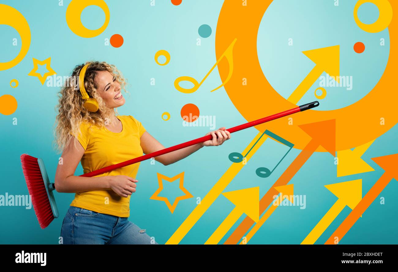 Fille avec casque utiliser le balai comme une guitare. Fond cyan Banque D'Images