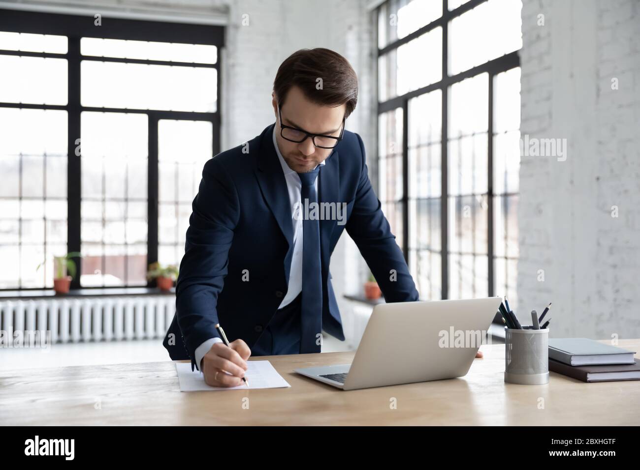 Un homme d'affaires sérieux travaille sur un ordinateur portable pour prendre des notes Banque D'Images