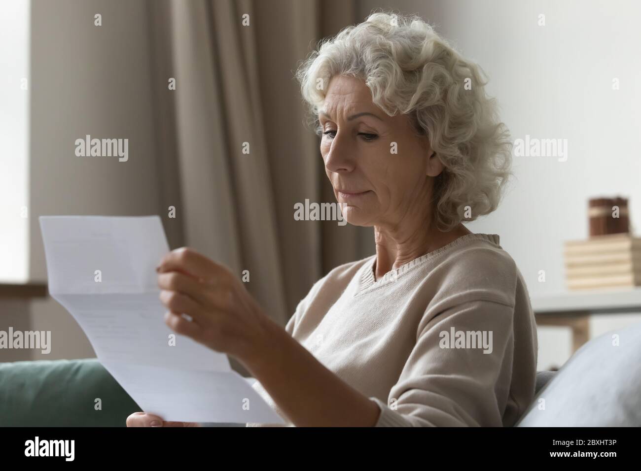 Une femme mûre concentrée a lu la lettre postale à la maison Banque D'Images