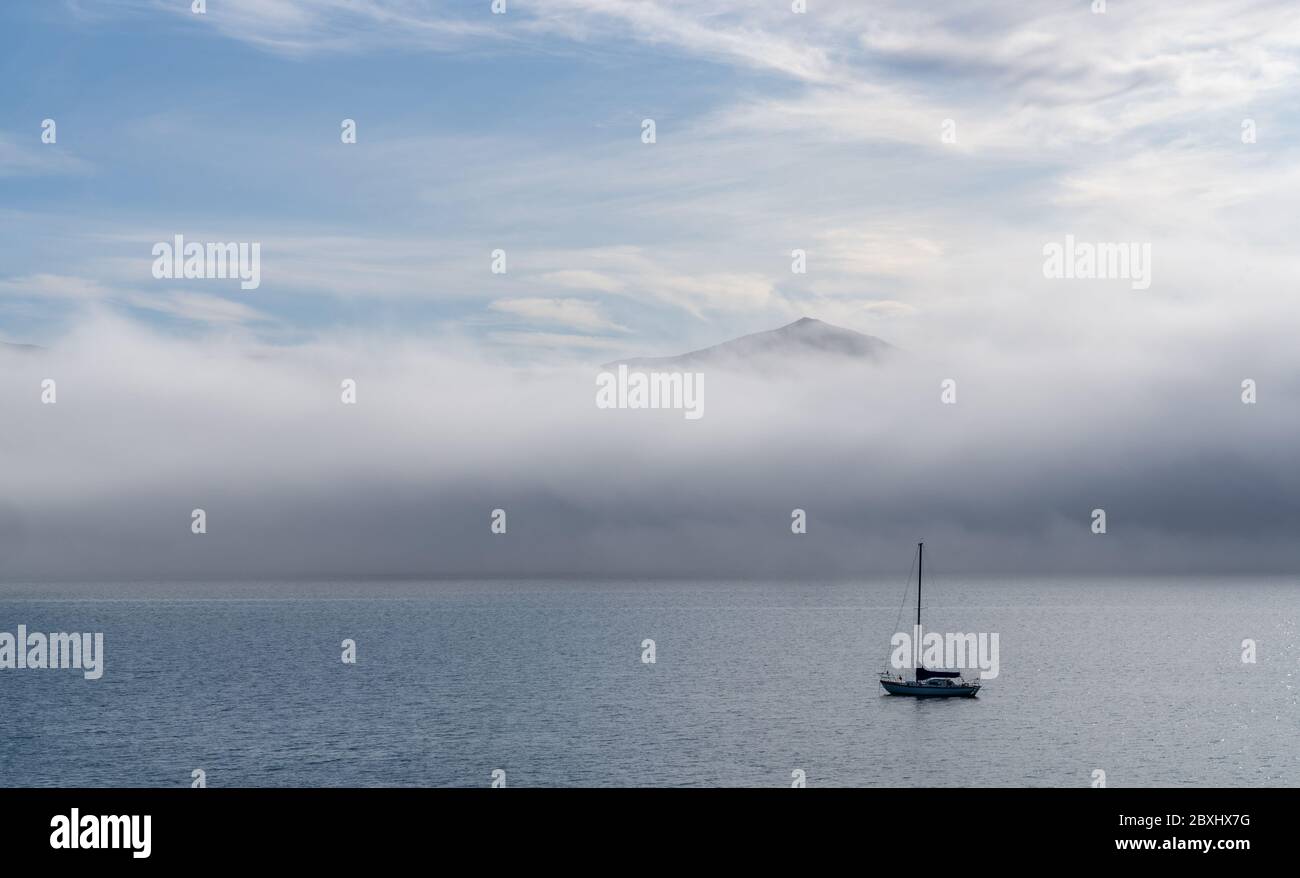 Ciel bleu, nuages blancs, brume et mer d'aigue-marine au port d'Akaroa. Les bateaux de pêche et voiliers sont ancrés le long du port d'Akaroa, Canterbury, New Zea Banque D'Images