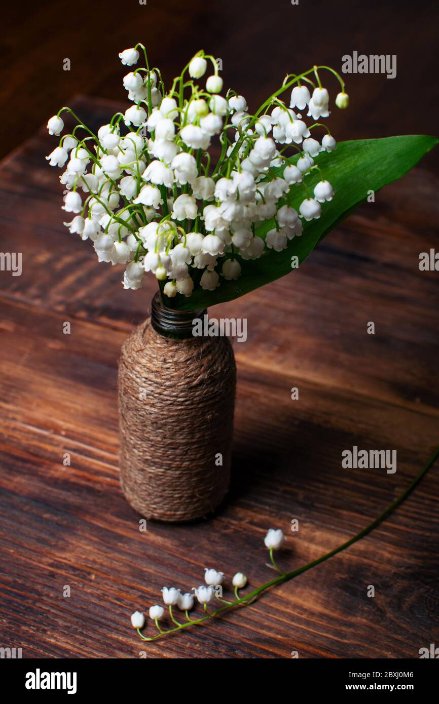 Délicat bouquet de nénuphars de la vallée dans un vase vintage sur une table en bois. Mise au point sélective. Banque D'Images