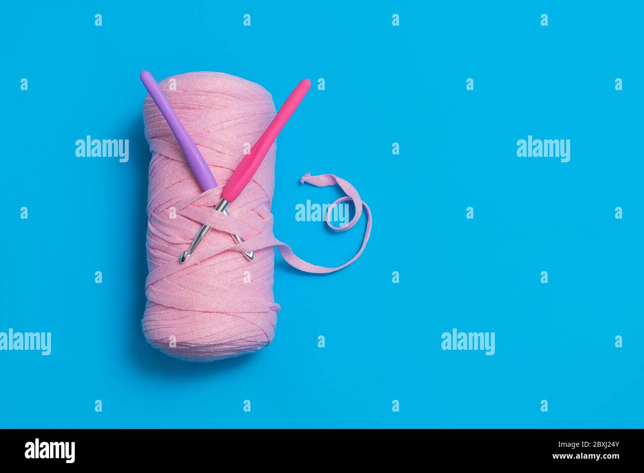 Directement au-dessus de la vue du fil de ruban avec crochets en crochet sur fond bleu. Fait à la main et concept de crocheting. Image avec espace pour le texte, vue de dessus Banque D'Images
