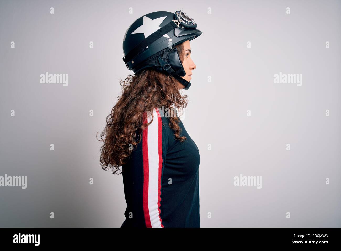 Belle moto femme avec cheveux bouclés portant un casque moto sur fond blanc  regardant de côté, détendez-vous profil pose avec visage naturel avec conf  Photo Stock - Alamy