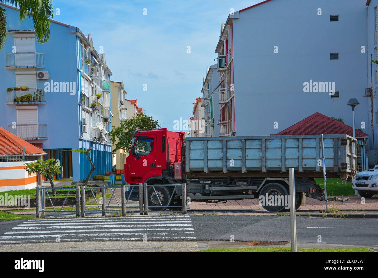 Point-a-Pitre, Guadeloupe - 17 septembre 2018 : le chauffeur a garé un camion avec cabine rouge sur le trottoir près d'une traversée piétonne entre les maisons bleues Banque D'Images