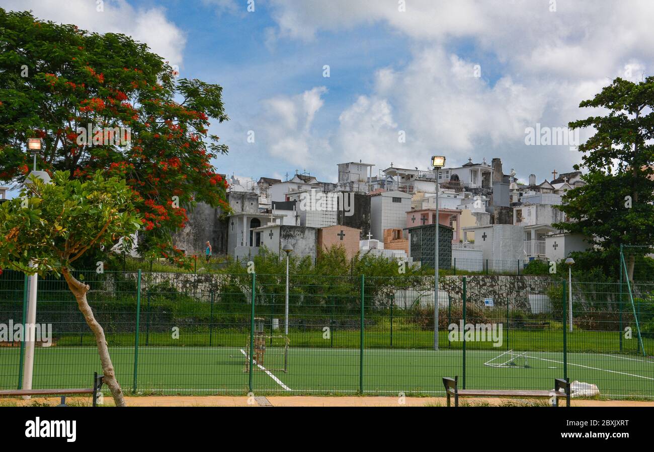 Point-a-Pitre, Guadeloupe - 17 septembre 2018 : terrain de sport avec une surface verte en arrière-plan du cimetière. Ciel bleu et nuages blancs. Copier l'espace Banque D'Images