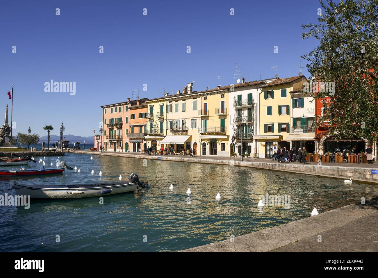 Vue sur le port de la vieille ville sur les rives du lac de Garde avec des bateaux de pêche amarrés dans le canal d'eau, Lazise, Vérone, Vénétie, Italie Banque D'Images