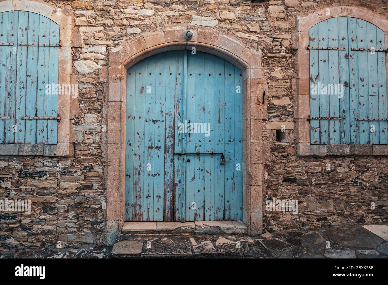 Porte en bois bleu fermée et fenêtres dans la vieille brique de pierre Chypre bâtiment extérieur. Banque D'Images