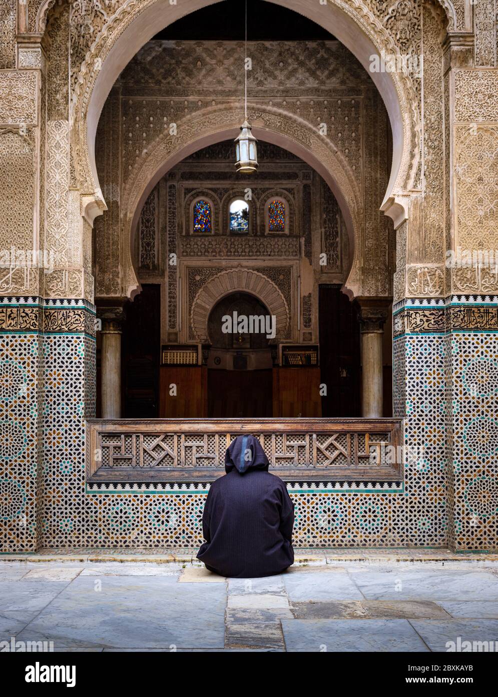 FÈS, MAROC - VERS MAI 2018 : homme marocain assis dans la cour de la Madrasa Al-Attarine à Fès. La cour de ce petit Marinid madrasa moi Banque D'Images