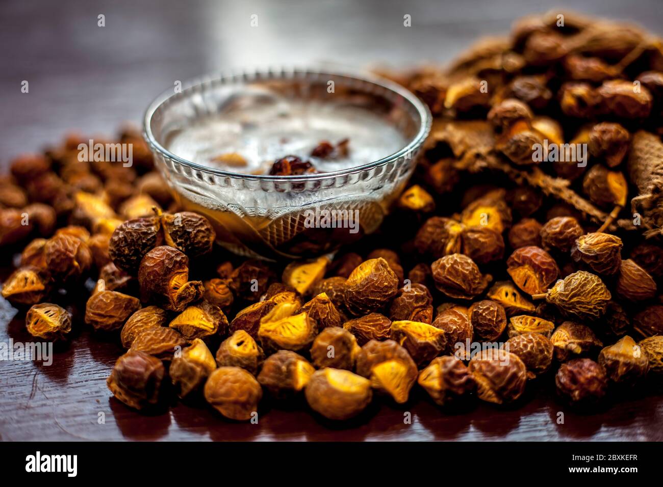 Une prise de soapnut, de reetha ou d'aréetha dans un sac de tireur avec un peu de son shampooing naturel dans un bol en verre. Banque D'Images