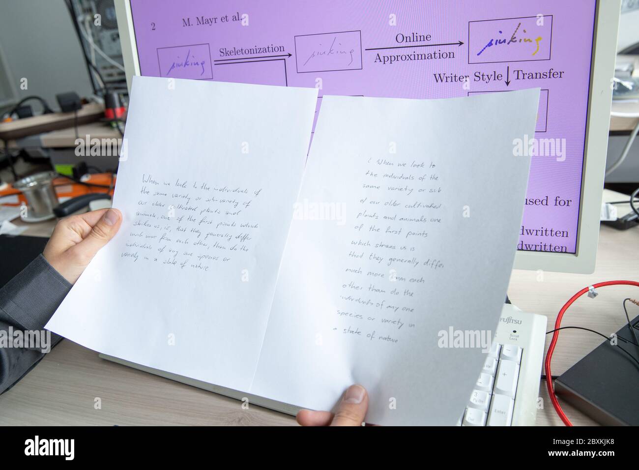 05 juin 2020, Bavière, Erlangen: Un assistant de recherche de la Chaire de reconnaissance de patrons à l'Université d'Erlangen-Nuremberg tient des imprimés d'un texte de patrons entre ses mains. Le texte de gauche est manuscrit, le texte de droite est généré automatiquement avec l'algorithme pour l'imitation d'écriture dans le style de l'original. Les chercheurs d'Erlangen utilisent l'intelligence artificielle pour imiter l'écriture manuscrite. Un des objectifs est de permettre aux gens d'écrire des textes dans leur propre écriture manuscrite qui ne sont plus en mesure d'écrire eux-mêmes en raison de blessures ou d'autres déficiences. Photo: Daniel Karmann/dpa Banque D'Images