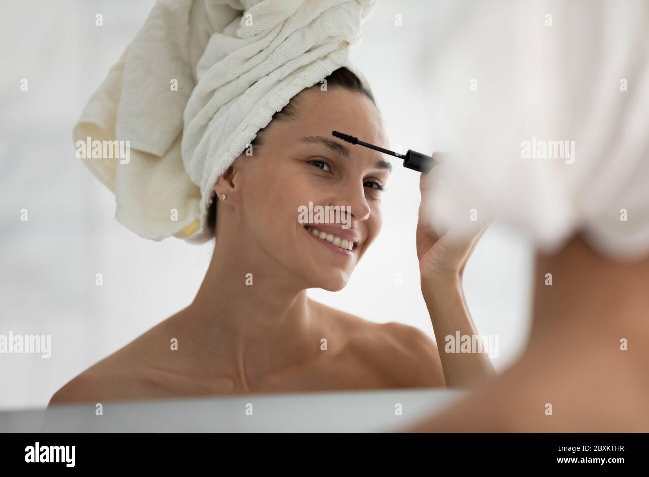 Tête de tir sourire femme appliquant mascara noir sur les cils Banque D'Images