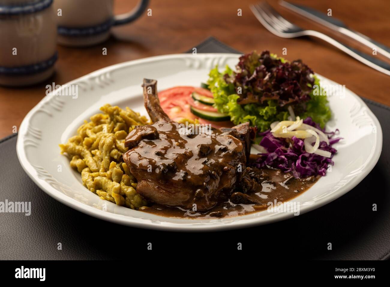steak d'oeil côtelé avec salade de spaetzle sur tapis en cuir et table en bois sur fond flou Banque D'Images