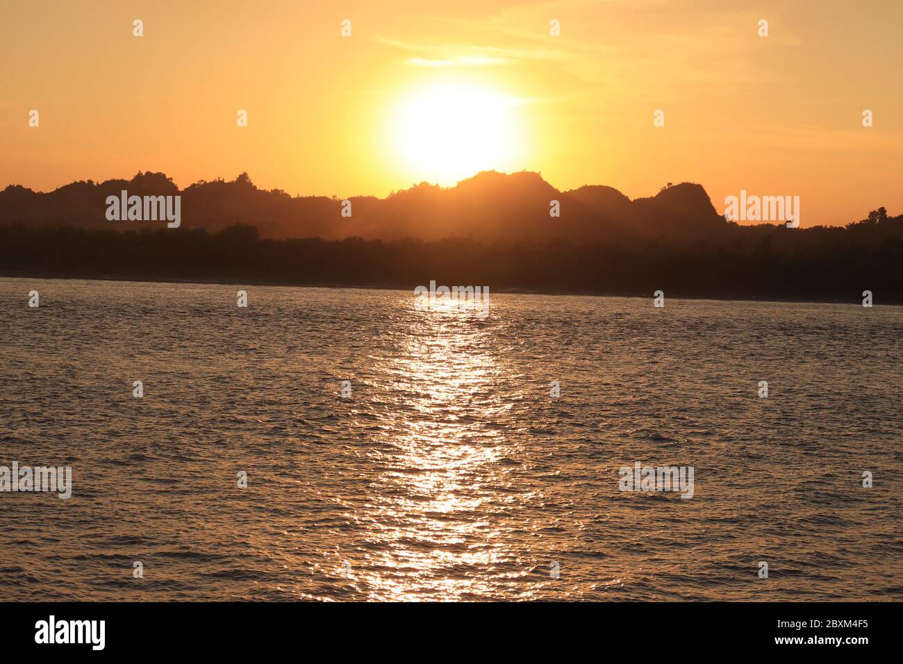 Ciel de coucher de soleil avec silhouette de colline et de rivière au crépuscule. Banque D'Images