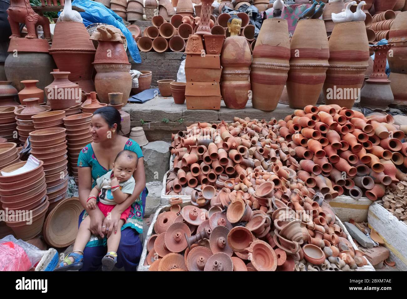 Un vendeur et son tout-petit assis parmi des centaines de poteries à vendre au marché de la poterie, au nord d'Indra Chowk, Katmandou, Népal, Banque D'Images