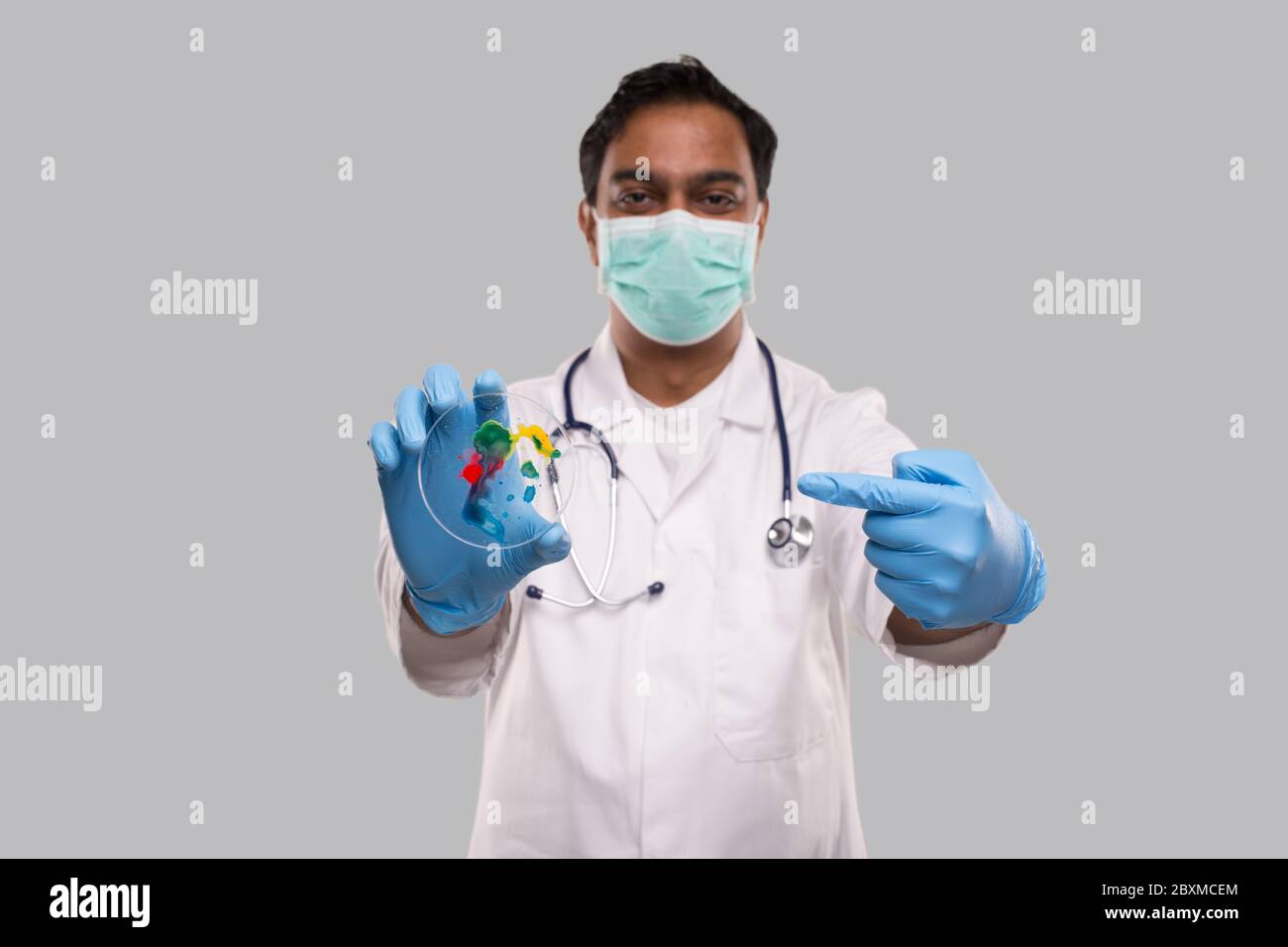Médecin pointant vers une boîte de Petri portant un masque médical et des gants isolés. Médecine, concept de la science Banque D'Images