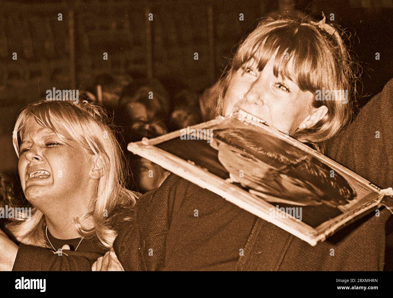 Beatles dans les années 1960. Fans d'un concert des Beatles à Stockholm le 1964 juillet 28 sur le stadion de Johanneshov. Photo d'une scène du concert et de l'auditoire qui est en extacy. La fille à droite tient un portrait de Ringo Starr dans sa bouche. Banque D'Images