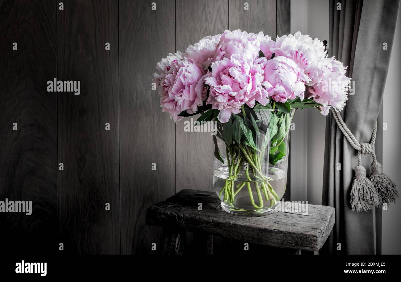 Pivoines roses dans un vase sur une table rustique en bois. Décoration romantique. Banque D'Images