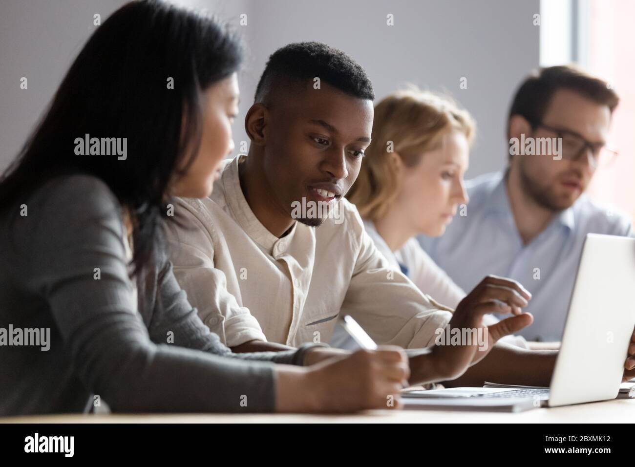 Des collègues multiethniques assis dans la salle de travail des collègues discutent de la nouvelle application d'entreprise Banque D'Images