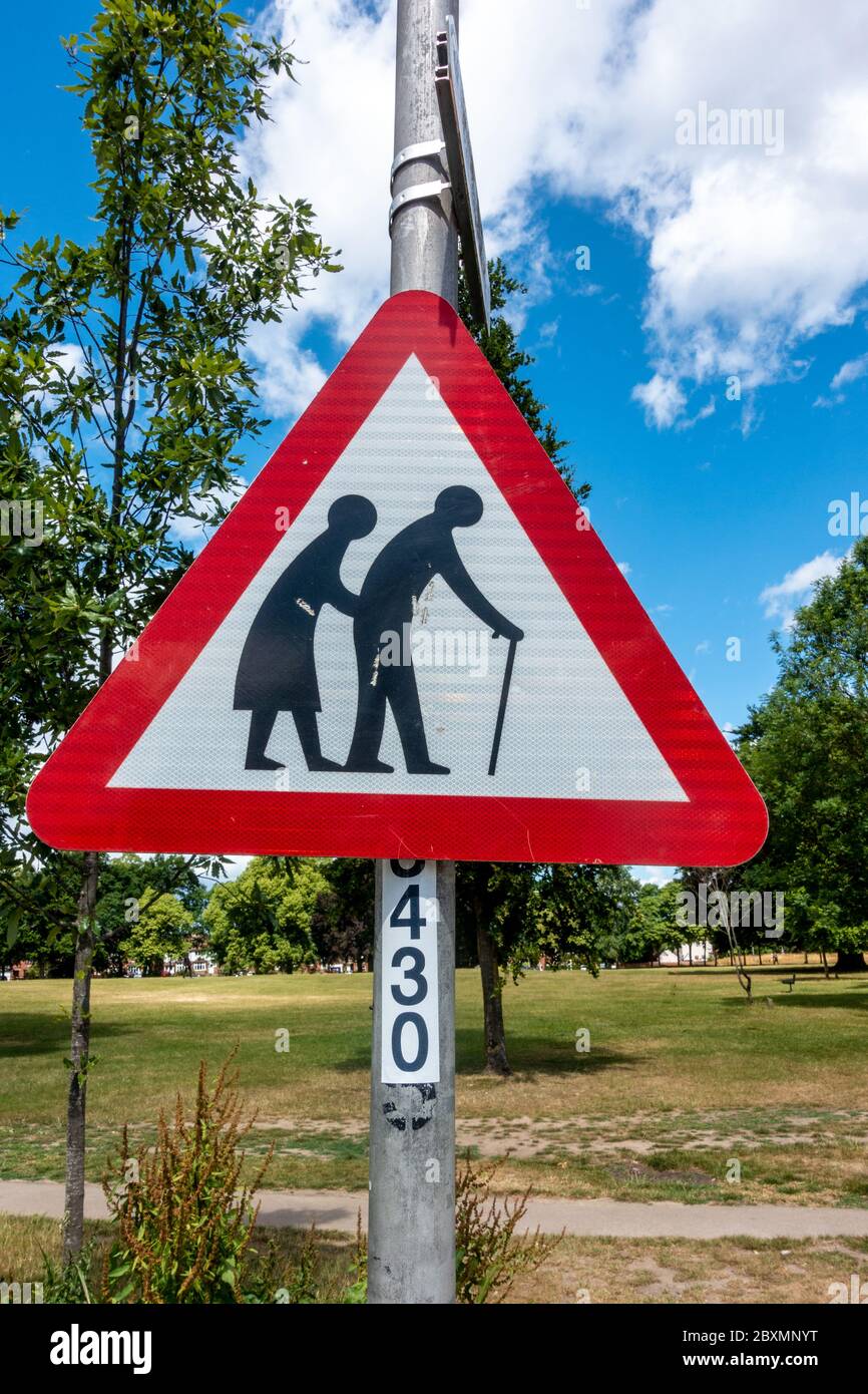 Un panneau triangulaire rouge dans un parc avertit les piétons qui pourraient être lents ou instables en raison de leur âge ou de leur manque d'fermeté. Banque D'Images