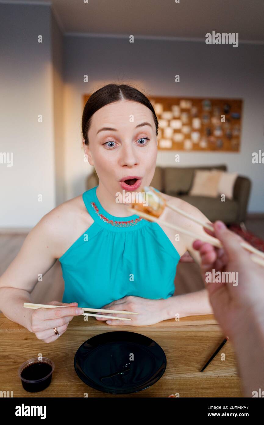 Surprise femme anticipe le goût de son sushi rouler en s'asseyant à la table passer du temps dans son salon à la maison Banque D'Images