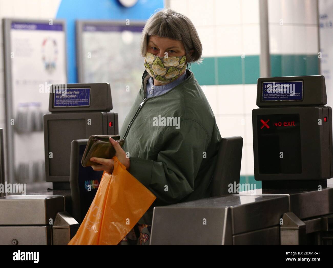 Une femme porte un masque facial lorsqu'elle sort des barrières tarifaires de la station de métro Brixton, dans le sud de Londres. A partir de lundi, les revêtements doivent être portés pour toute la durée des trajets sur le réseau de transport public, dans le cadre des nouvelles mesures introduites par le gouvernement pour aider à stopper la propagation du coronavirus. Banque D'Images