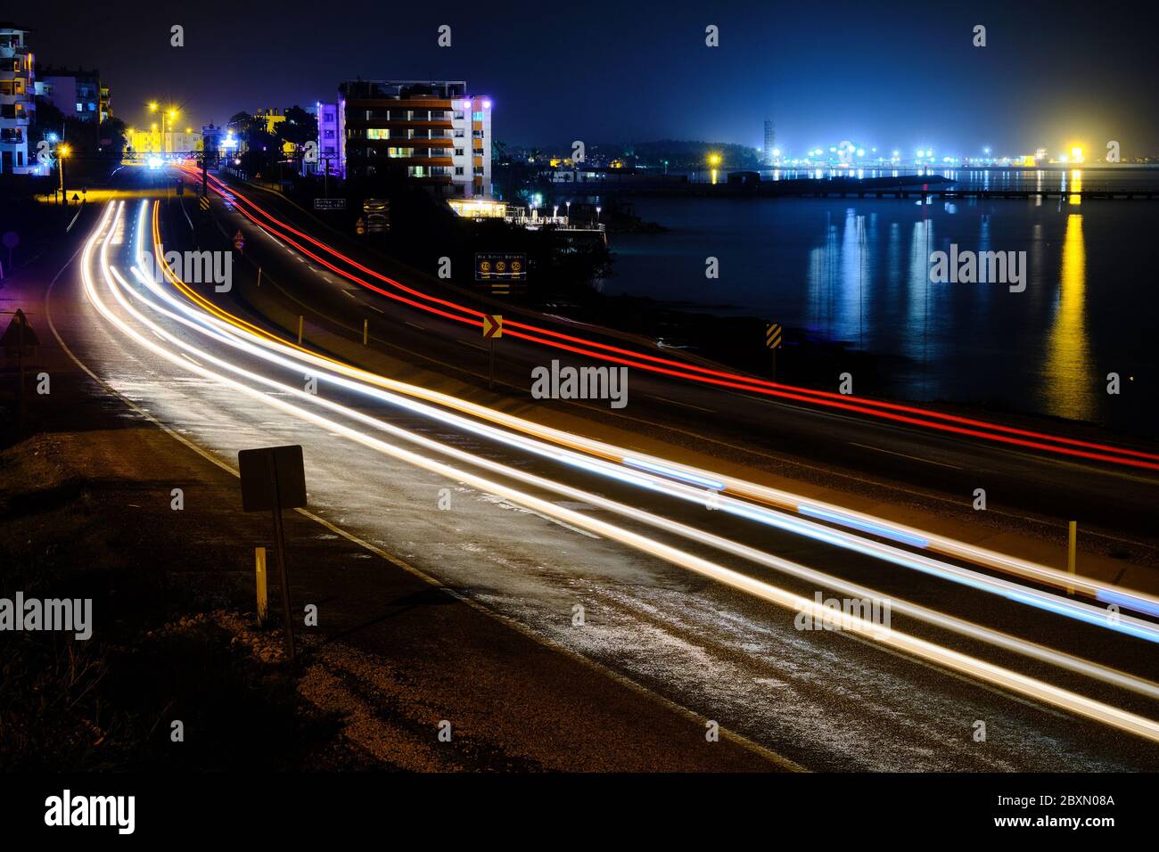 Des pistes lumineuses de voitures sur l'autoroute du bord de mer en pleine exposition nocturne. Banque D'Images