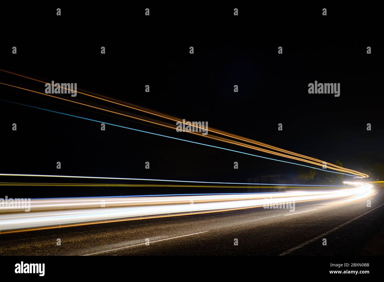Des pistes lumineuses de voitures sur l'autoroute en pleine exposition nocturne. Banque D'Images