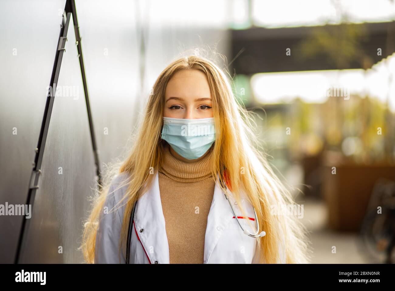 Portrait de femme médecin ou infirmière en masque chirurgical et robe médicale blanche vous regardant Banque D'Images