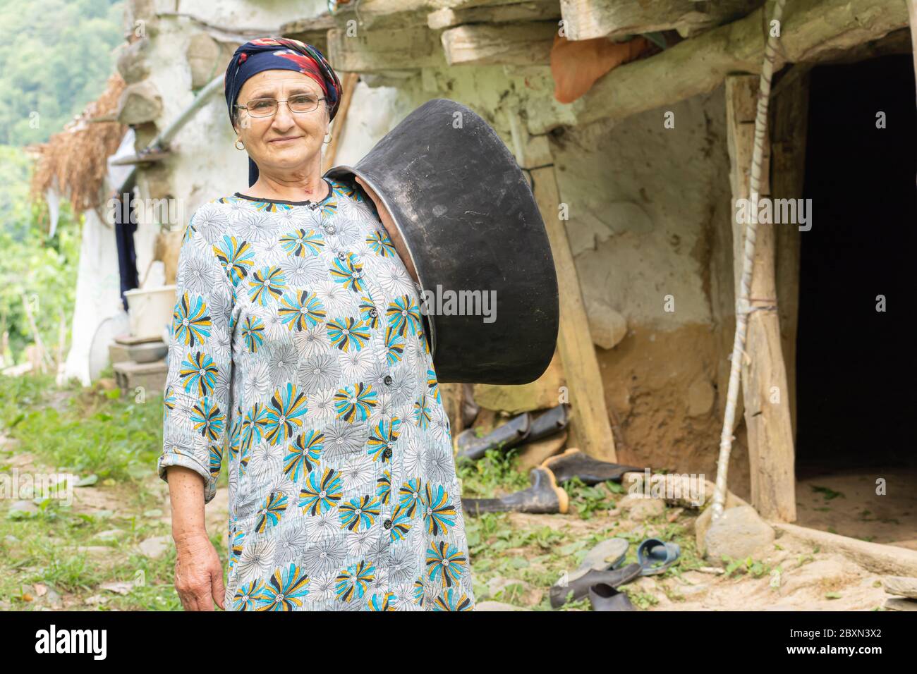 Portrait d'une femme musulmane senior sur un tissu traditionnel tenant un pot vintage devant l'épaule Banque D'Images