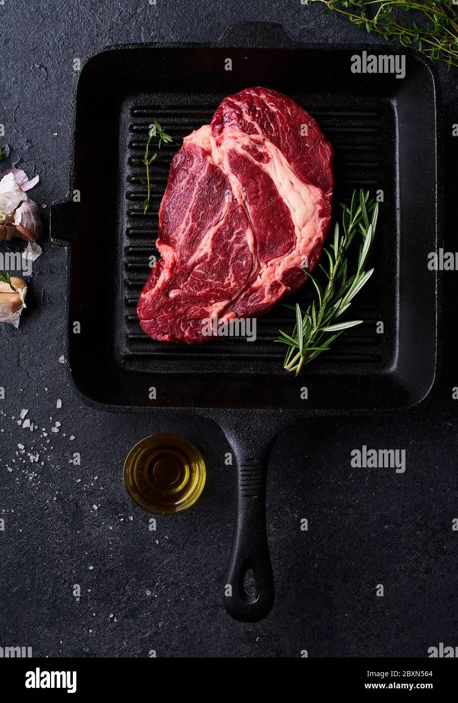 Vue du haut Black Angus Prime Beef Chuck roulé steak sur une poêle en fonte  avec romarin frais, thym, huile d'olive, ail et épices. Mise en page  créative avec Photo Stock -
