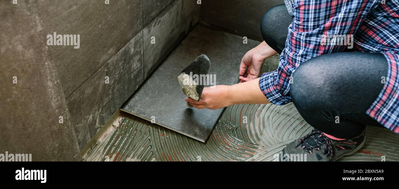 Femme ouvrier posant un nouveau plancher de carrelage Banque D'Images