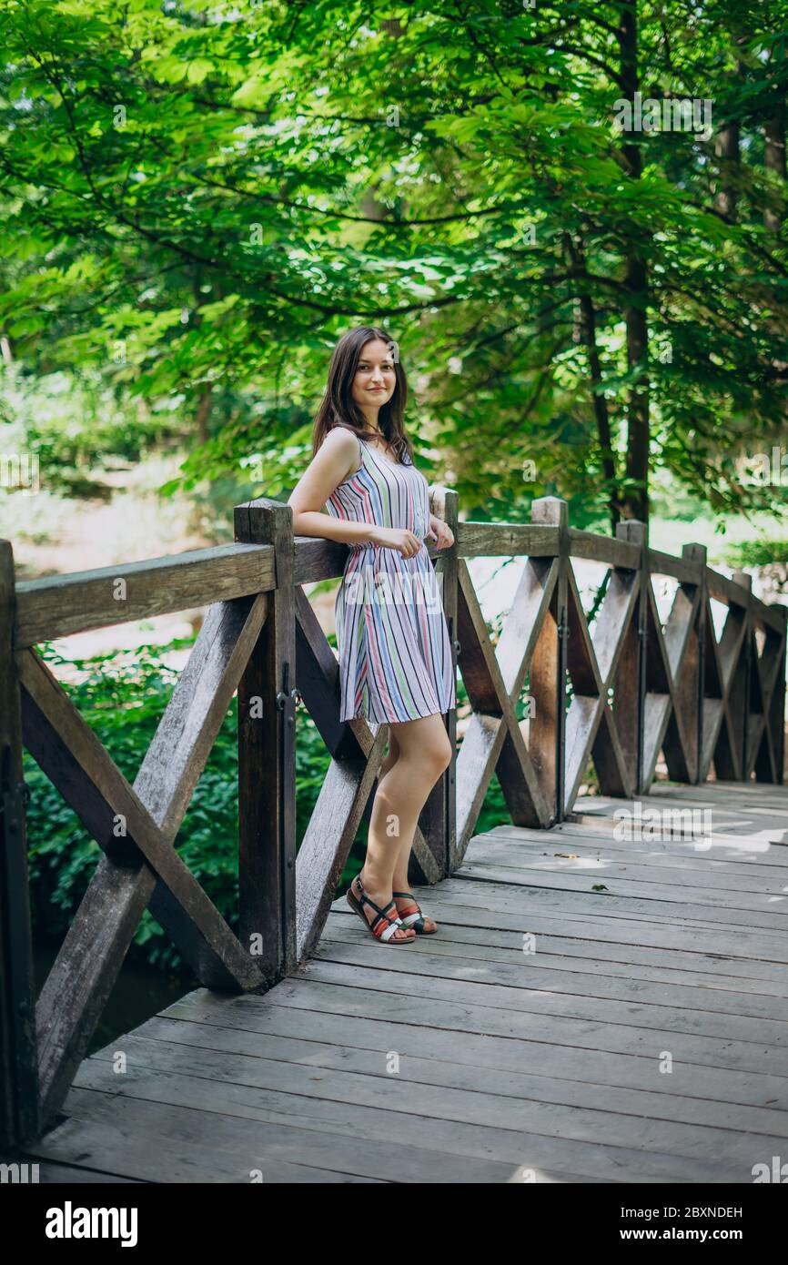 Parc Sofia, Uman. Fille souriante dans un panneau d'été sur un pont en bois. La fille se tient sur le pont entre le parc d'été vert. Promenade dans le GRE d'été Banque D'Images