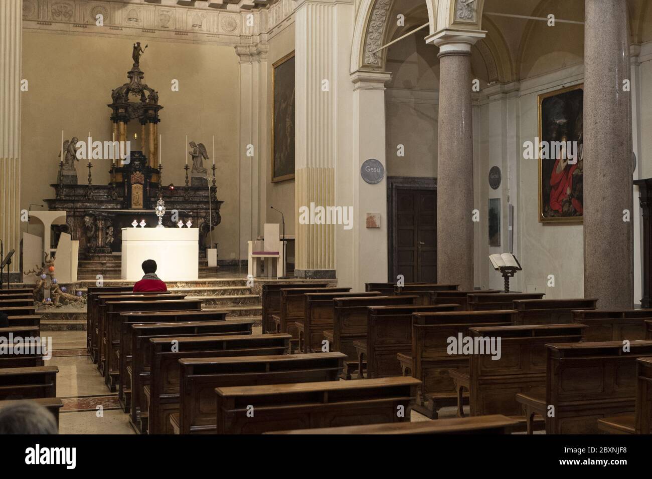 Une femme solitaire priant dans une église pendant le confinement dû à l'urgence Covid-19, à Milan, en Italie. Banque D'Images