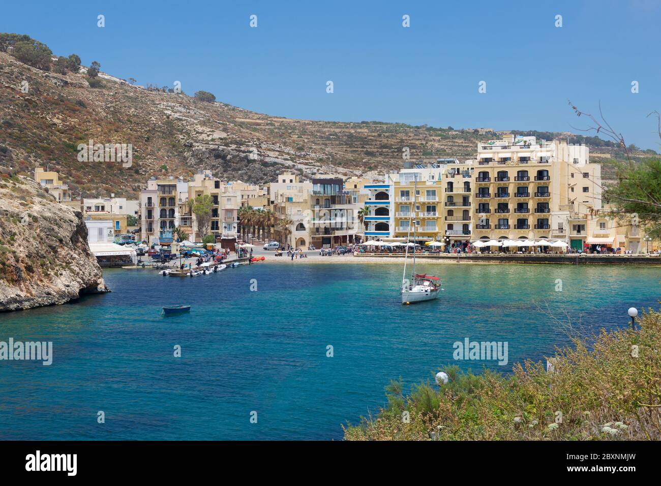 Baie de Xlendi sur l'île de Gozo à Malte avec de belles eaux bleu foncé et village historique de Xlendi. Eau bleu profond et plage de sable sur l'île de Gozo avec p Banque D'Images