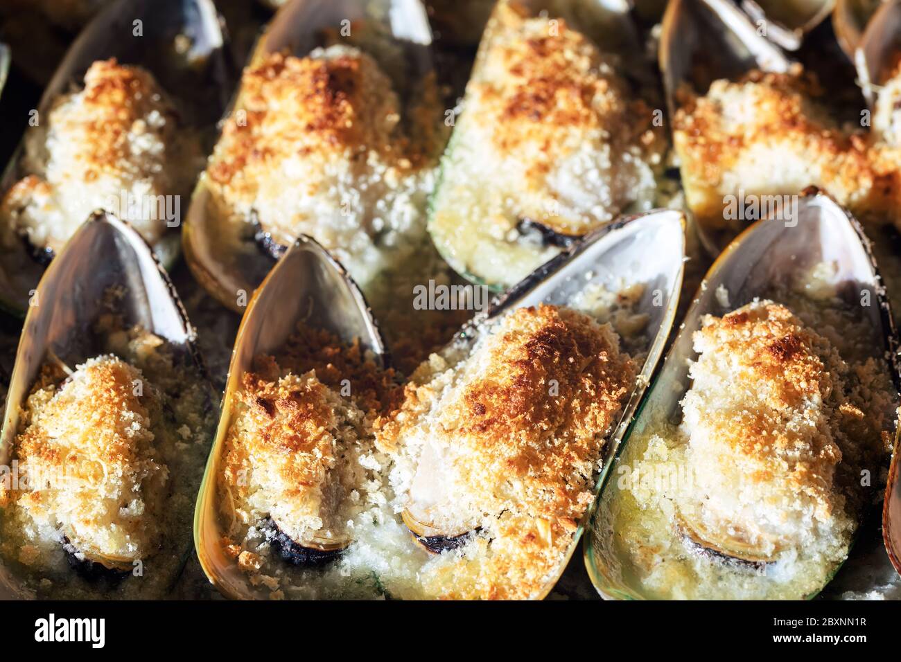 Moules cuites au parmesan, à la miette et au beurre aux herbes. La nourriture. Cuisine méditerranéenne. Concept pour un repas savoureux et sain. Gros plan. Banque D'Images