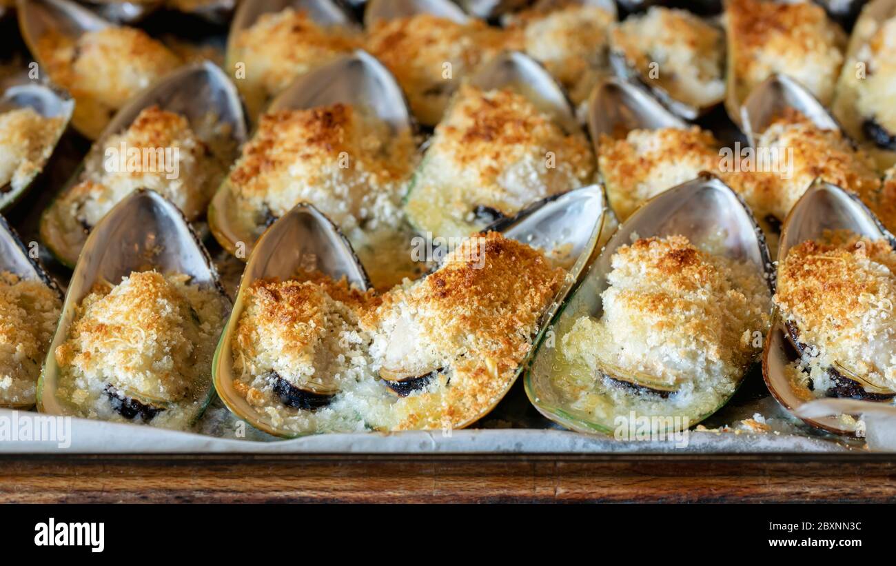 Moules cuites au parmesan, à la miette et au beurre aux herbes. La nourriture. Cuisine méditerranéenne. Concept pour un repas savoureux et sain. Gros plan. Banque D'Images