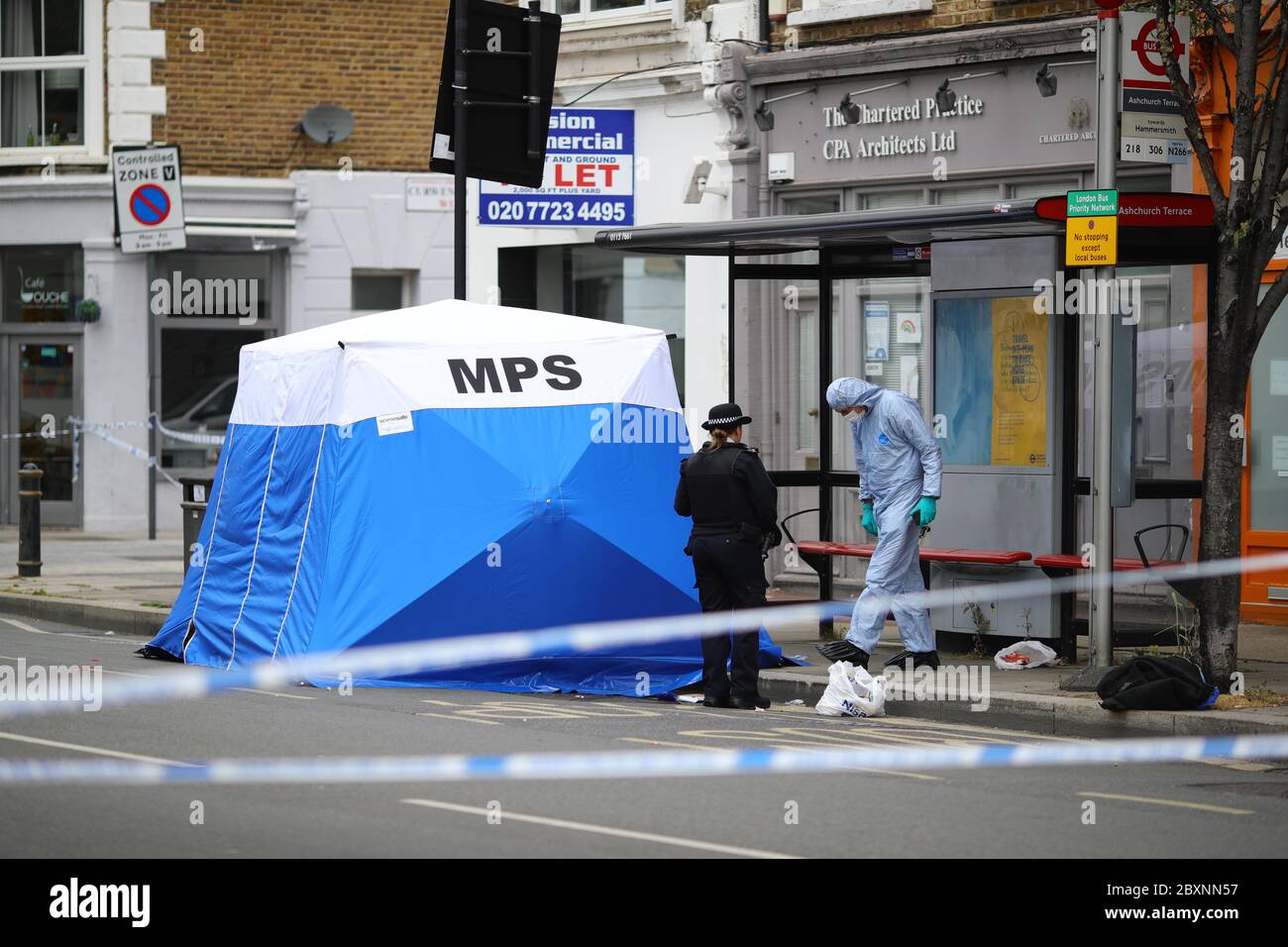 Un policier sous une tente de police sur les lieux de l'incident à Askew Road, Shepherd's Bush, dans l'ouest de Londres, alors qu'une enquête sur un meurtre a été lancée après qu'un homme ait été abattu. La victime, qui aurait été dans ses 20 ans, a été retrouvée avec des blessures par balle dans les premières heures de lundi. Banque D'Images