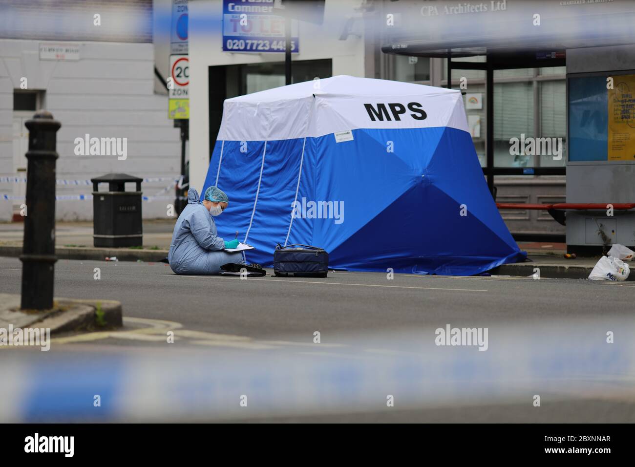 Un policier sous une tente de police sur les lieux de l'incident à Askew Road, Shepherd's Bush, dans l'ouest de Londres, alors qu'une enquête sur un meurtre a été lancée après qu'un homme ait été abattu. La victime, qui aurait été dans ses 20 ans, a été retrouvée avec des blessures par balle dans les premières heures de lundi. Banque D'Images