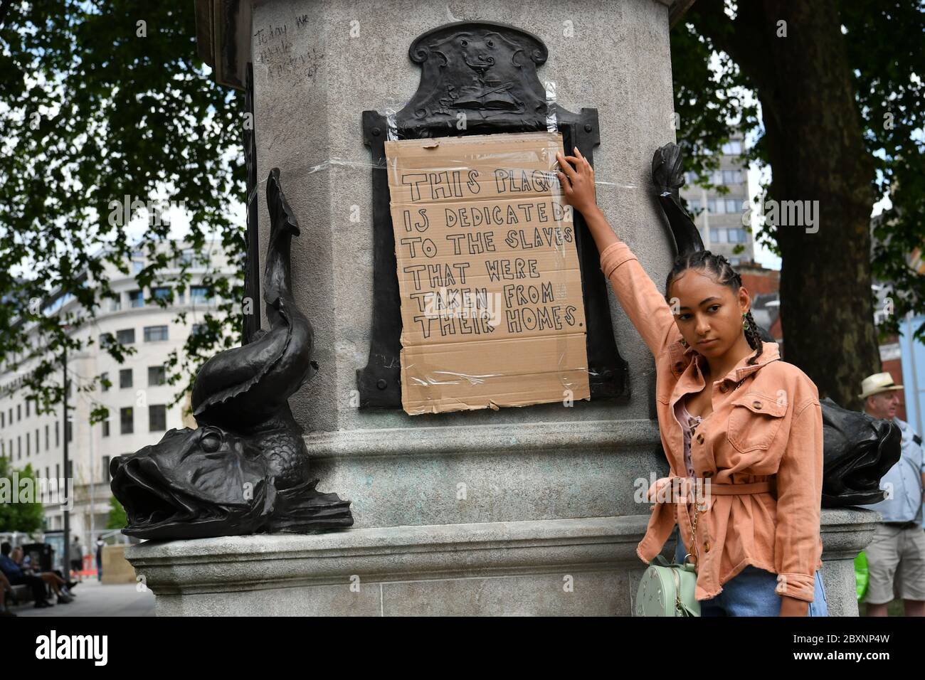 Asha (nom de famille non donné), 25 ans, de Bristol place son dévouement sur la plinthe vide où la statue d'Edward Colston à Bristol était autrefois debout après qu'elle ait été prise lors d'une manifestation Black Lives Matter dimanche. Les manifestations ont été déclenchées par la mort de George Floyd, qui a été tué le 25 mai alors qu'il était en garde à vue dans la ville américaine de Minneapolis. Banque D'Images