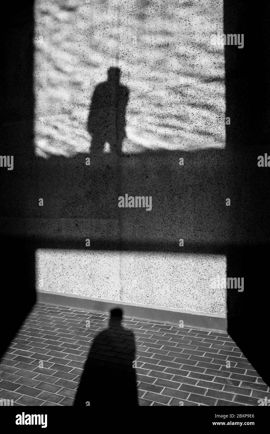 Photographie de rue en noir et blanc à Londres : ombre de la figure sur le mur et le sol. Banque D'Images