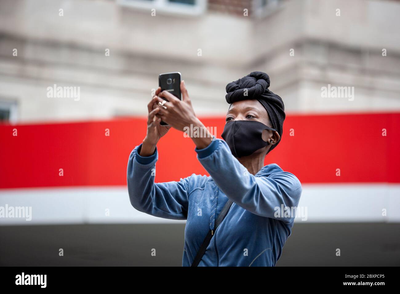 Femme, portant un foulard et un masque, tenant un téléphone portable pour filmer les manifestants de BLM au Royaume-Uni. Park Lane, Londres, Angleterre, Royaume-Uni Banque D'Images