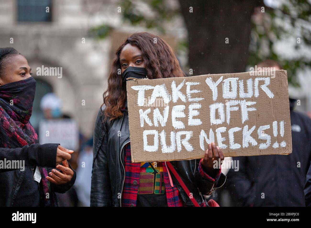 Jeune femme, portant un masque facial, tenant un panneau « Prenez votre genou hors de notre cou » à la Black Lives Matter UK Protest. Parliament Square, Londres, Royaume-Uni Banque D'Images