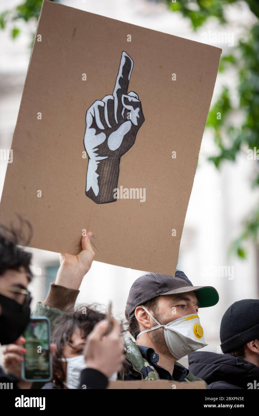 L'homme, portant un masque facial et une casquette de baseball, tient un panneau montrant, le symbole universel pour, le geste du doigt du milieu, à la manifestation BLM UK. Banque D'Images