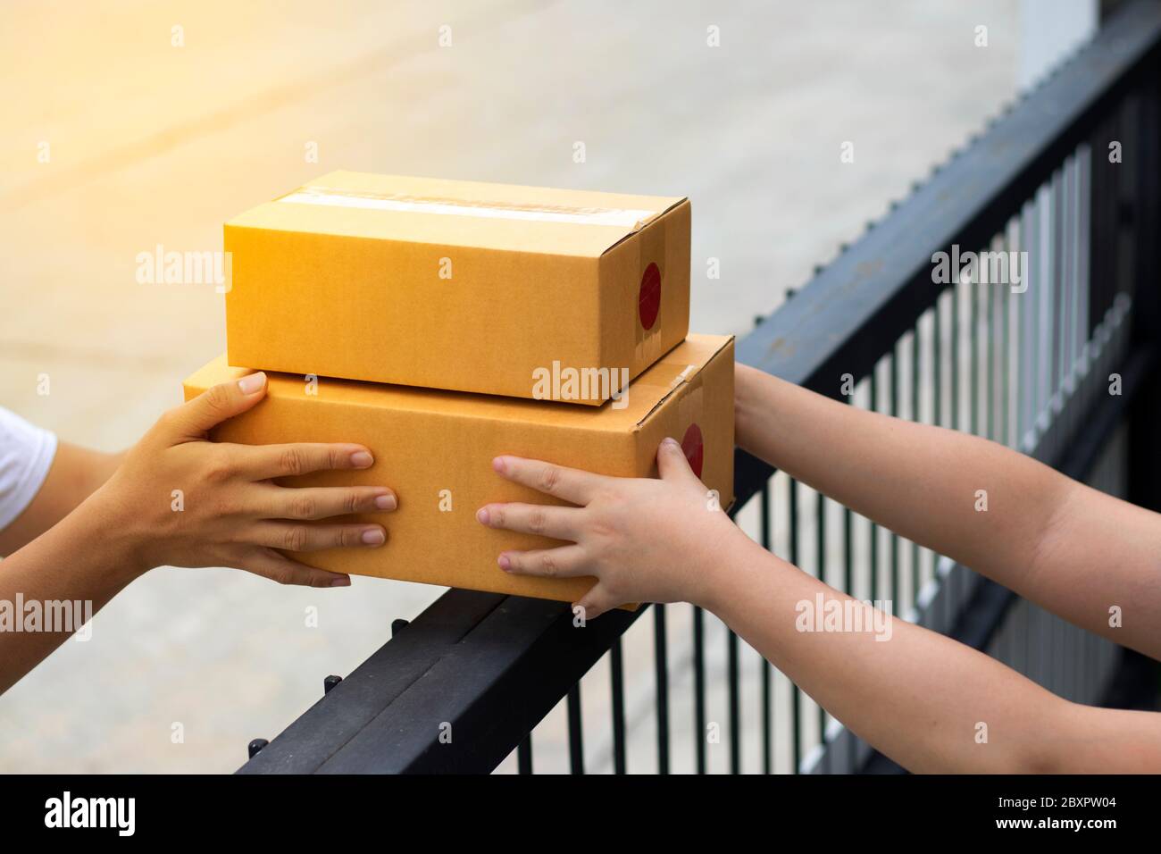 Le service de messagerie fournit la boîte marron au destinataire. La compagnie d'expédition livre les marchandises au destinataire à la porte d'entrée. Banque D'Images